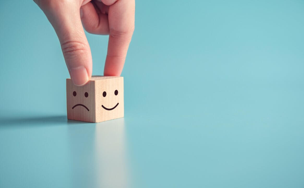 Close up customer hand choose smiley face and sad face icon on wood cube, Service rating, satisfaction concept, copy space.